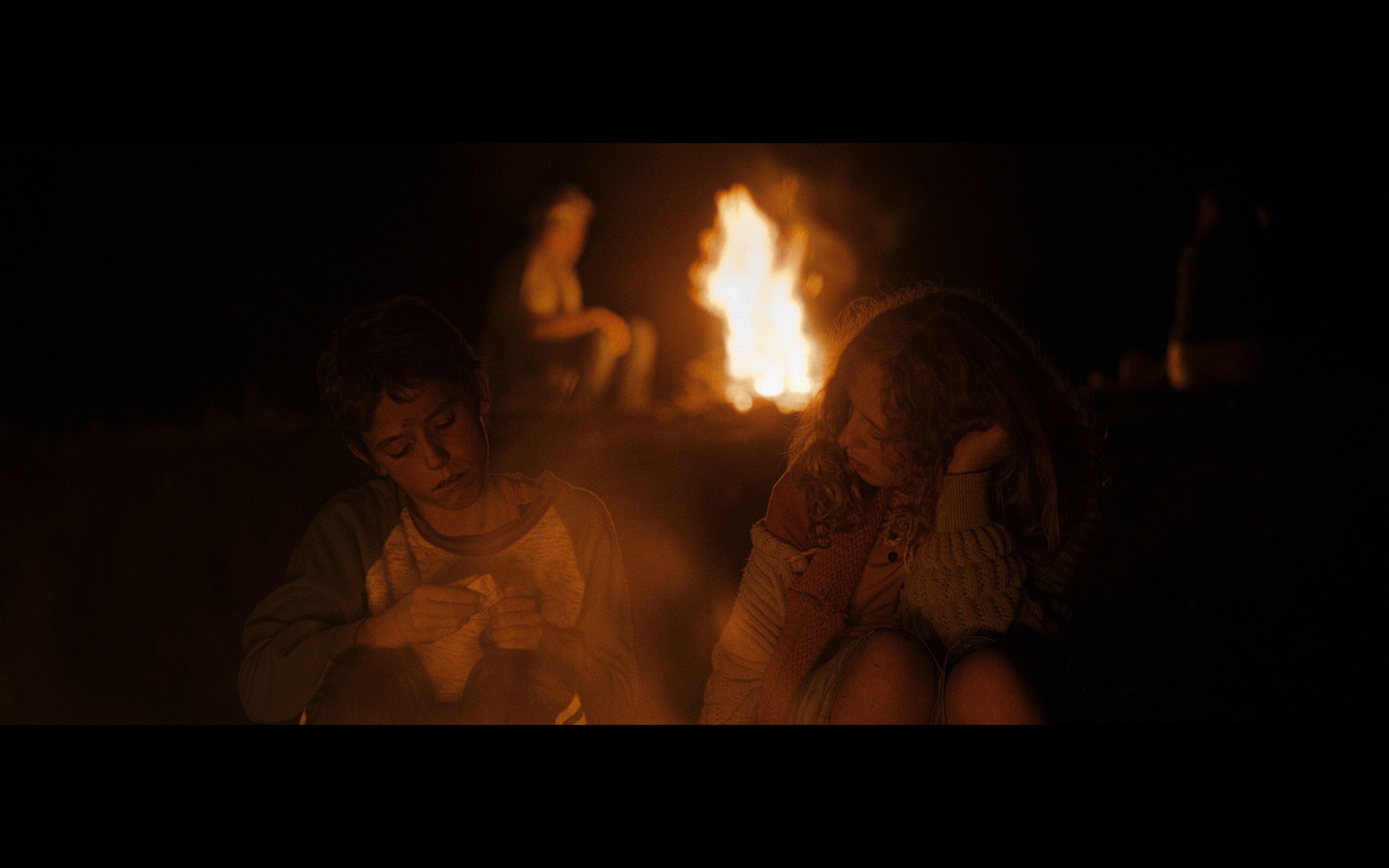 Two children beside a bonfire at night