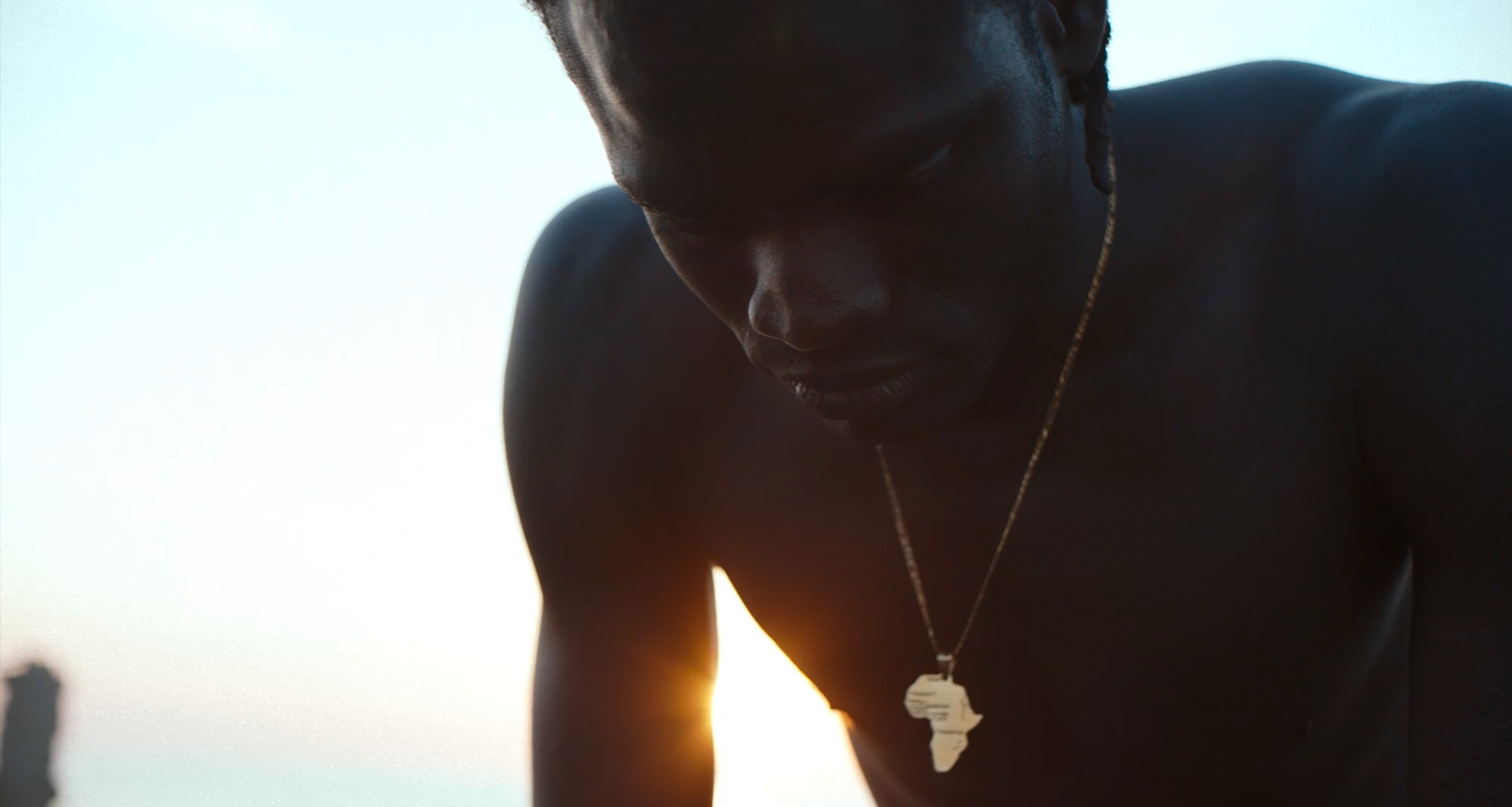 A close-up of a man backlit by the setting sun