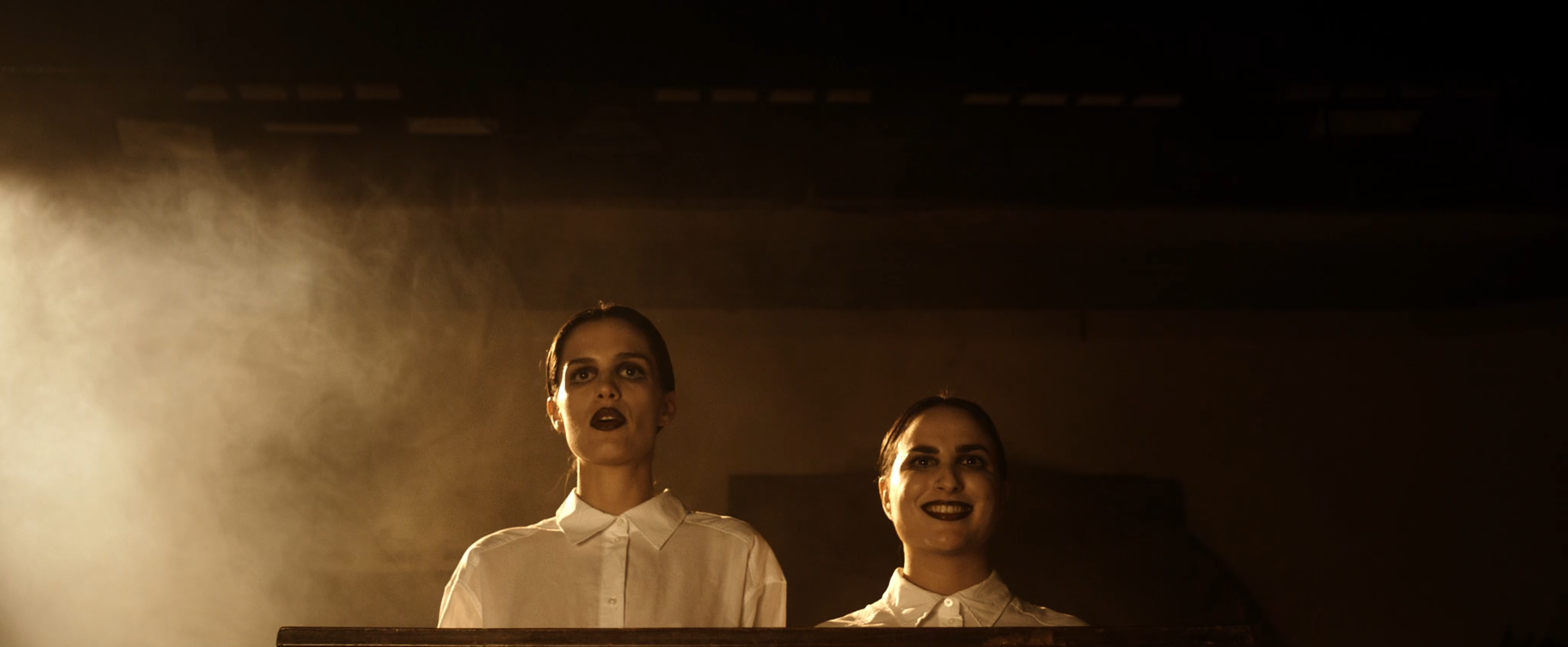 Two women in white shirts in a warmly lit room