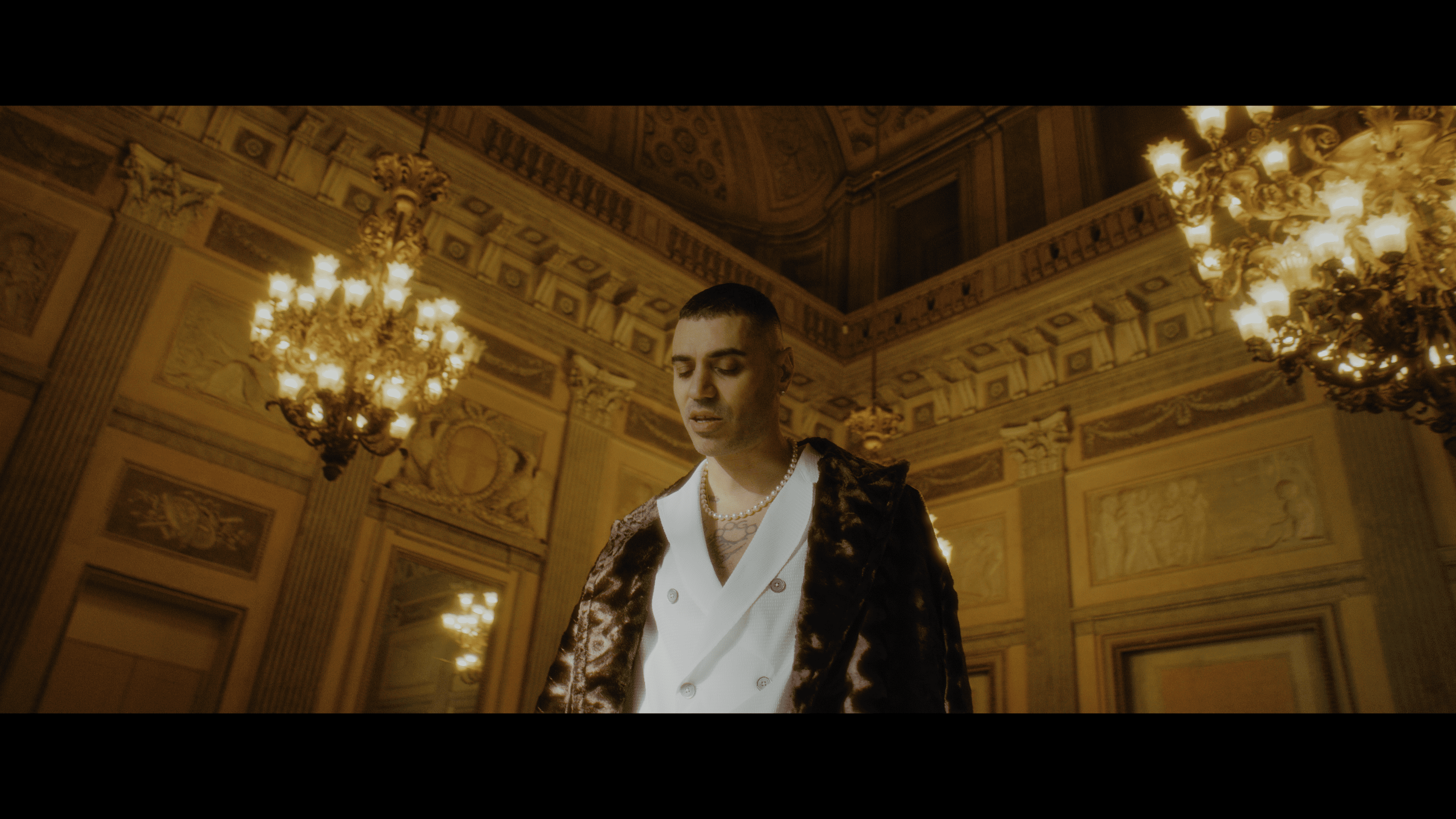 A portrait of an artist beneath chandeliers in golden light