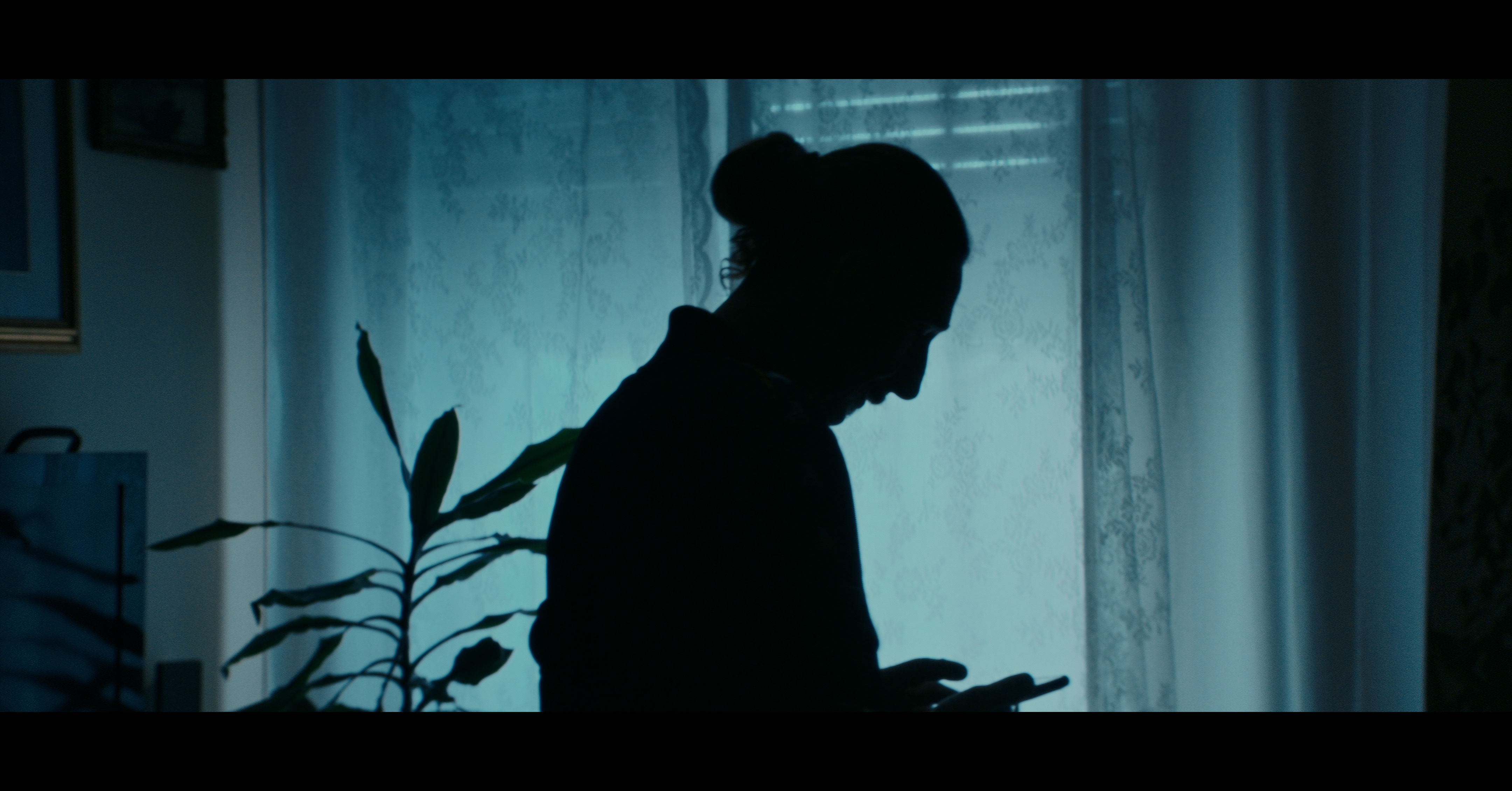 A silhouette beside a blue-lit window