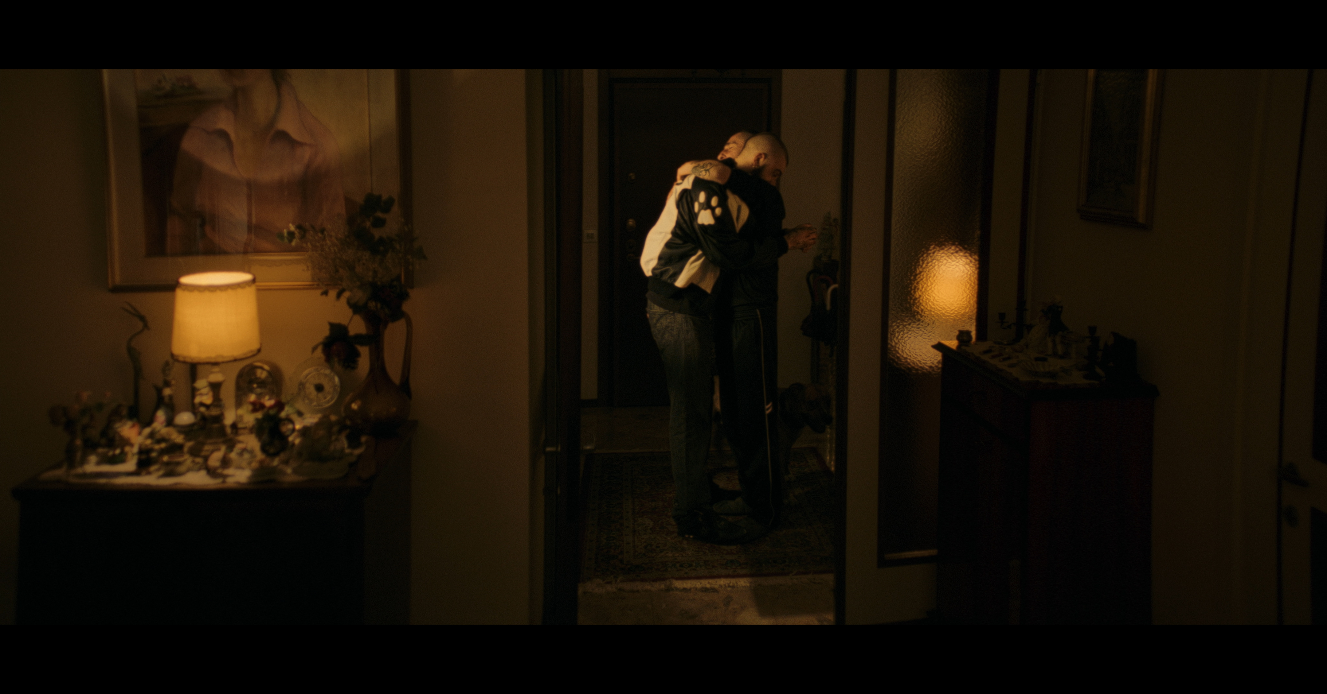 Two men embracing in a warmly lit doorway