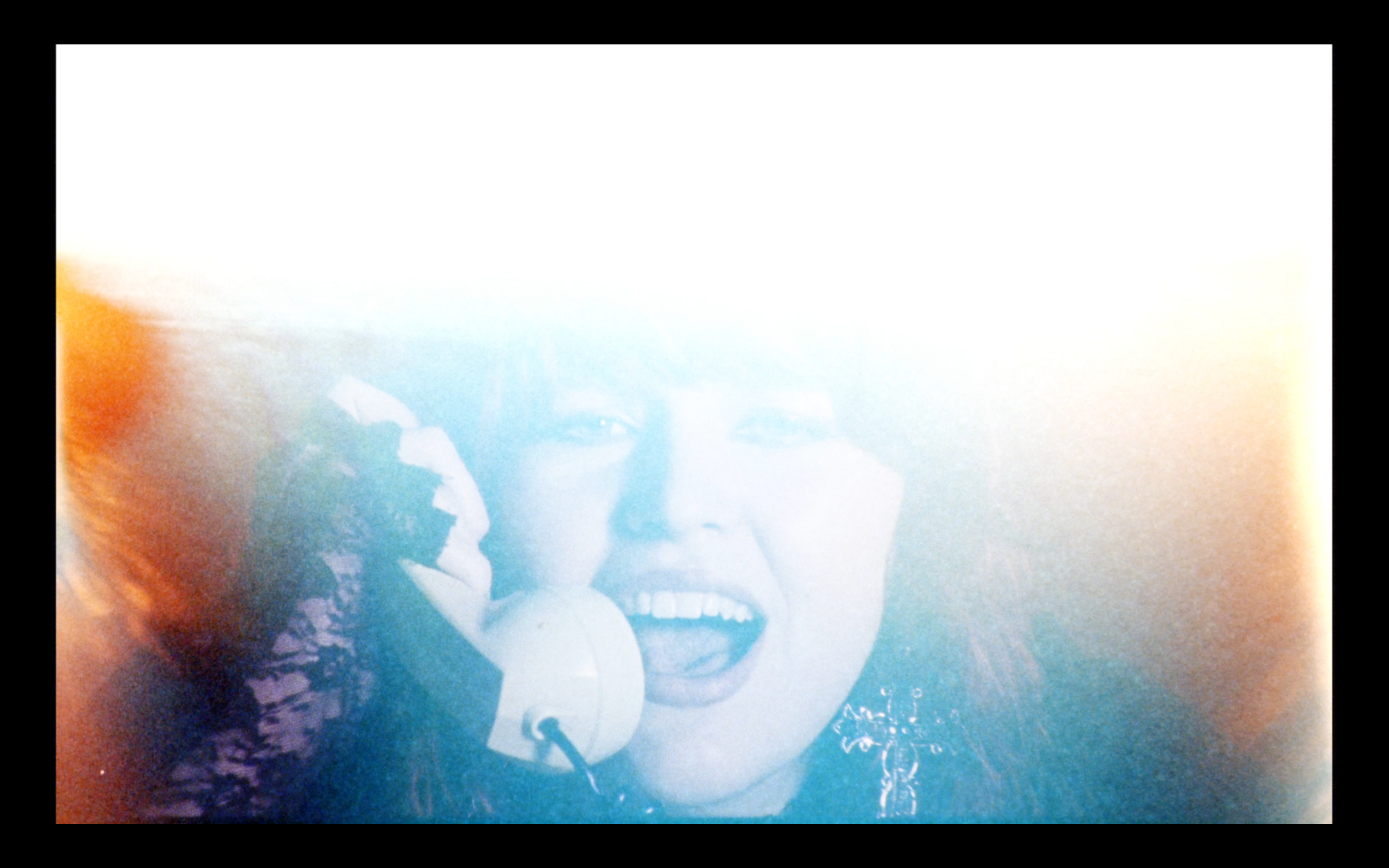Karin Ann holding a telephone beneath a bright film flare