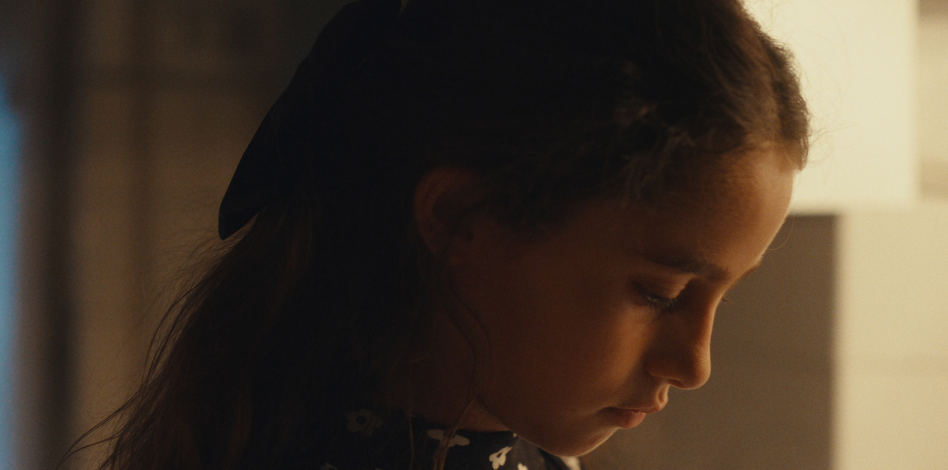 A close-up of a child looking down in warm light
