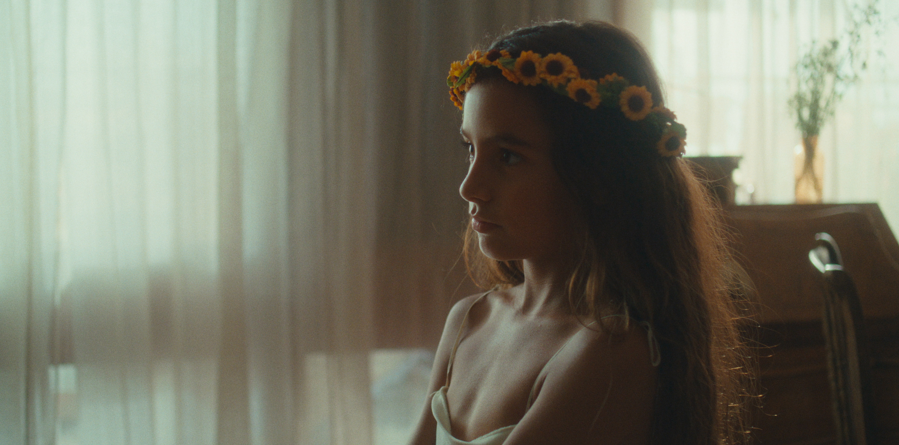 A child wearing a flower crown near the window