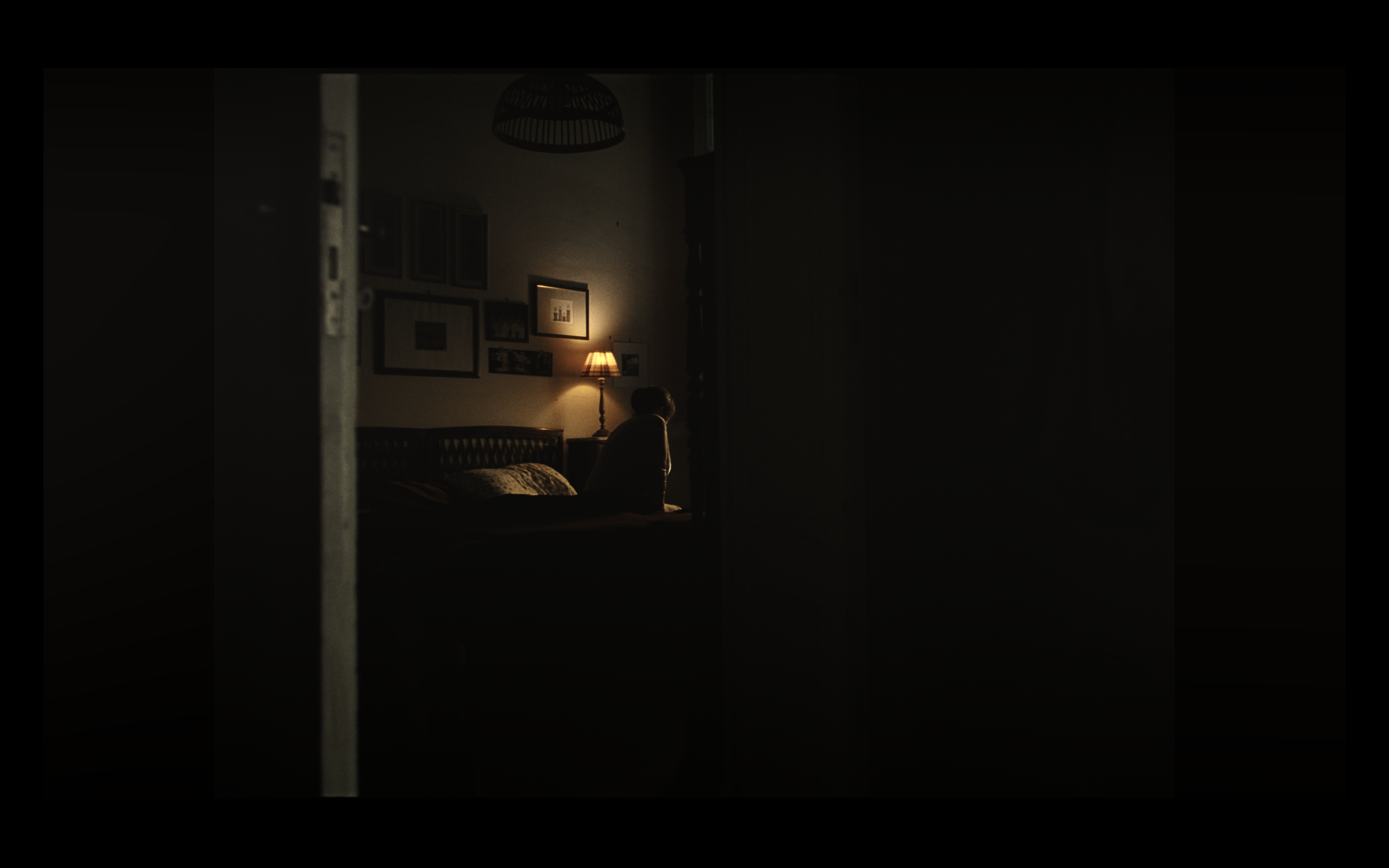 A woman sitting on a bed in a dimly lit room