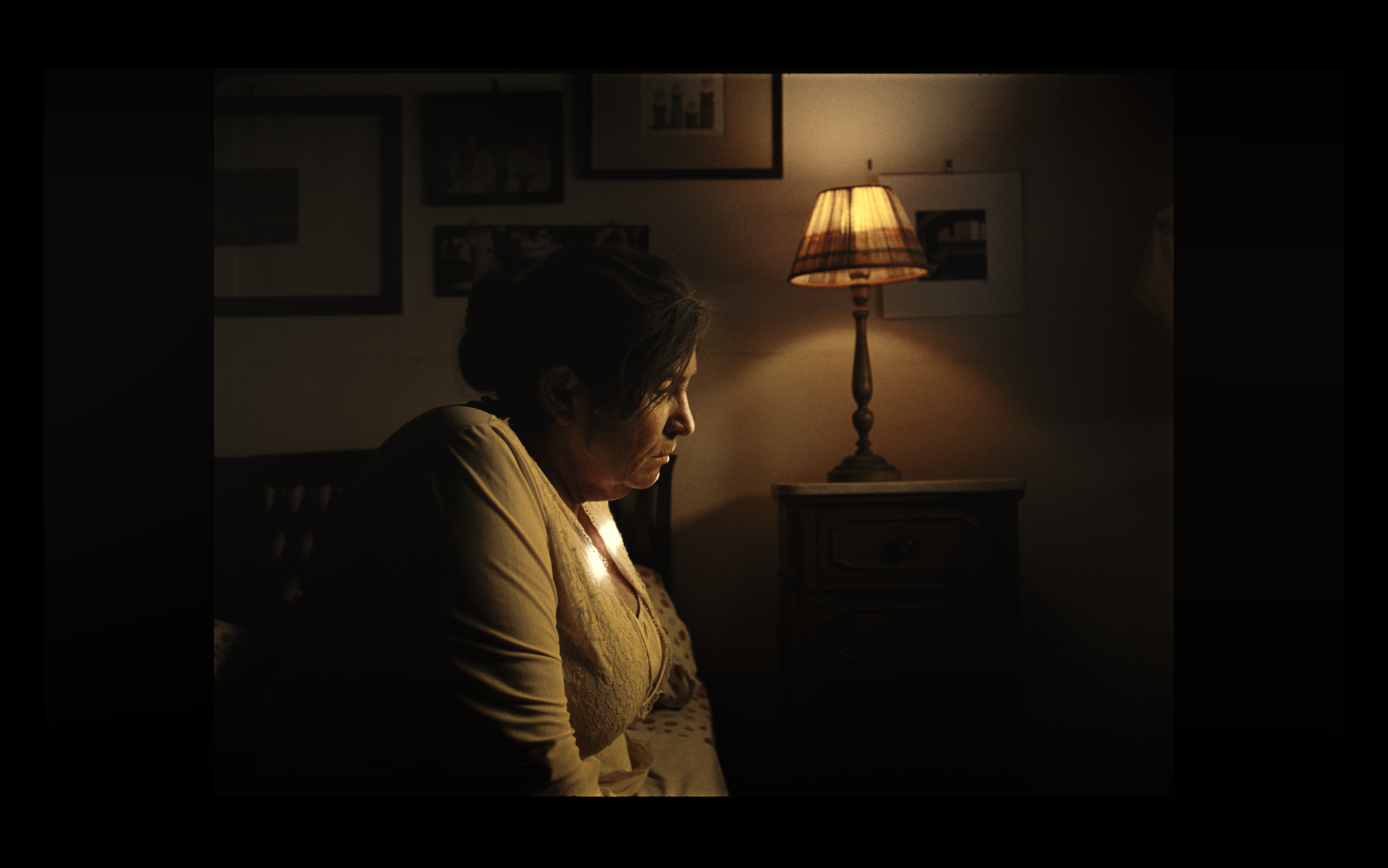 An older woman in profile beside a warm lamp