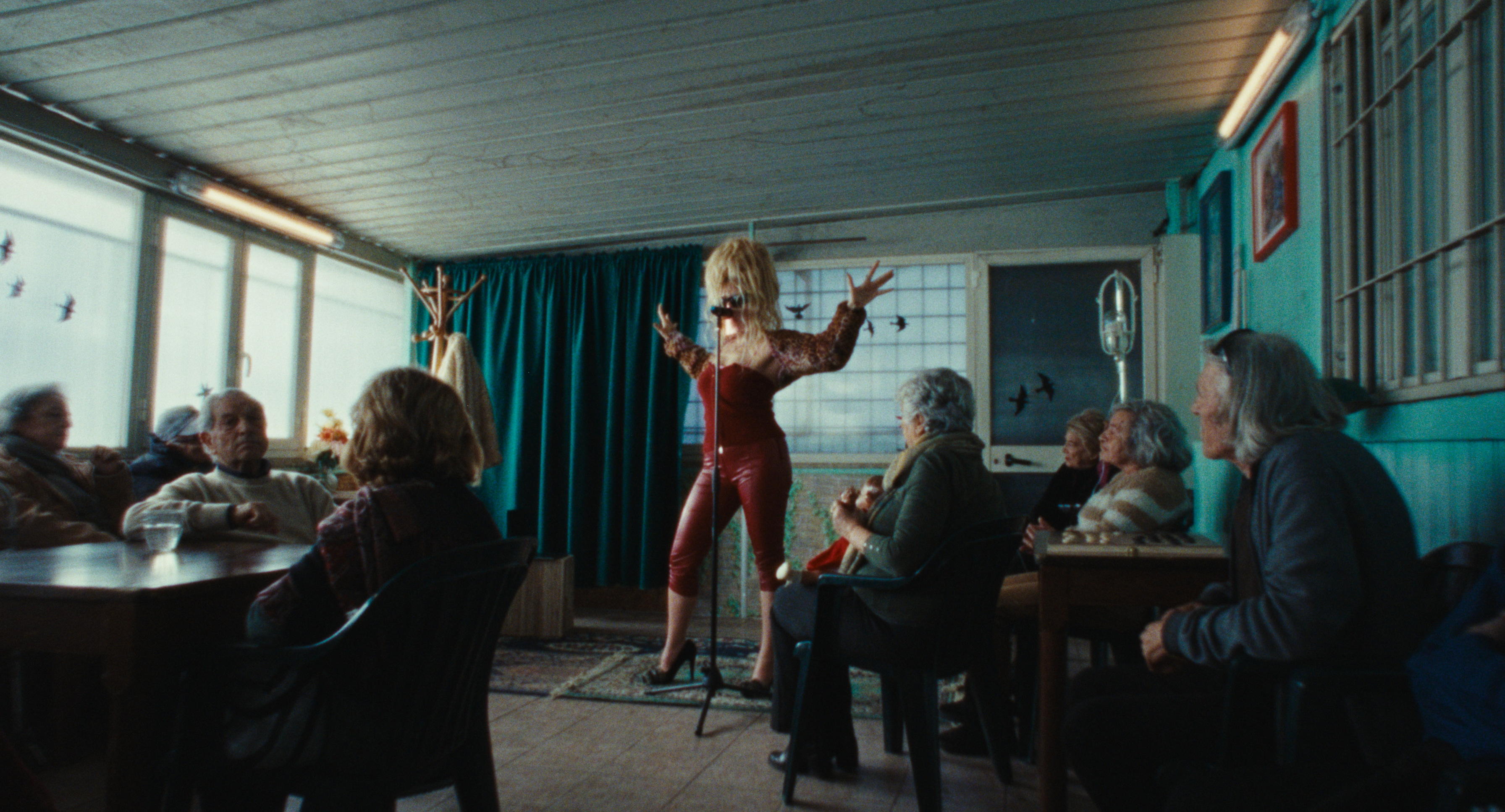 MYSSKETA performing between tables in a blue room