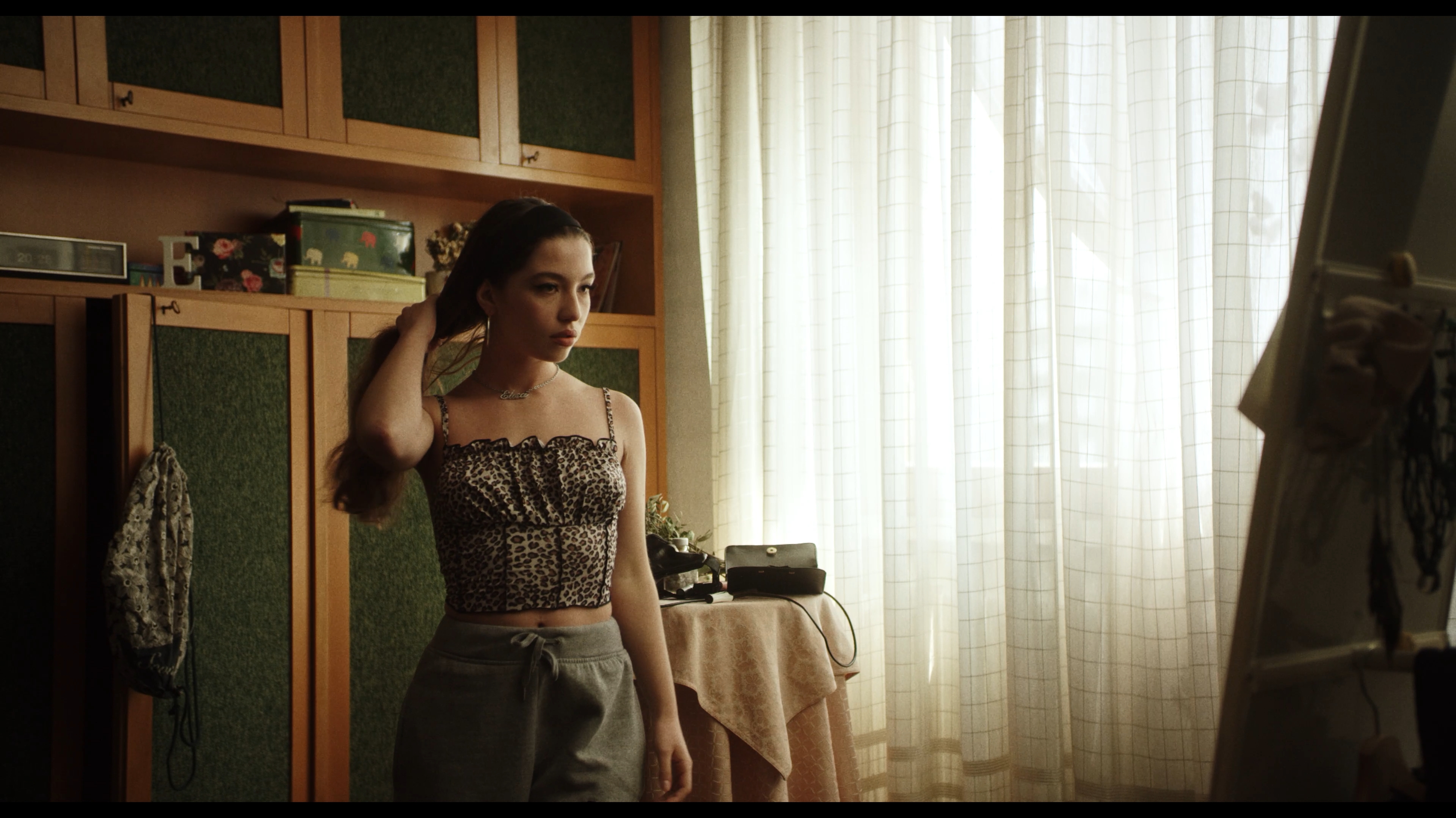 A woman standing beside a sunlit window