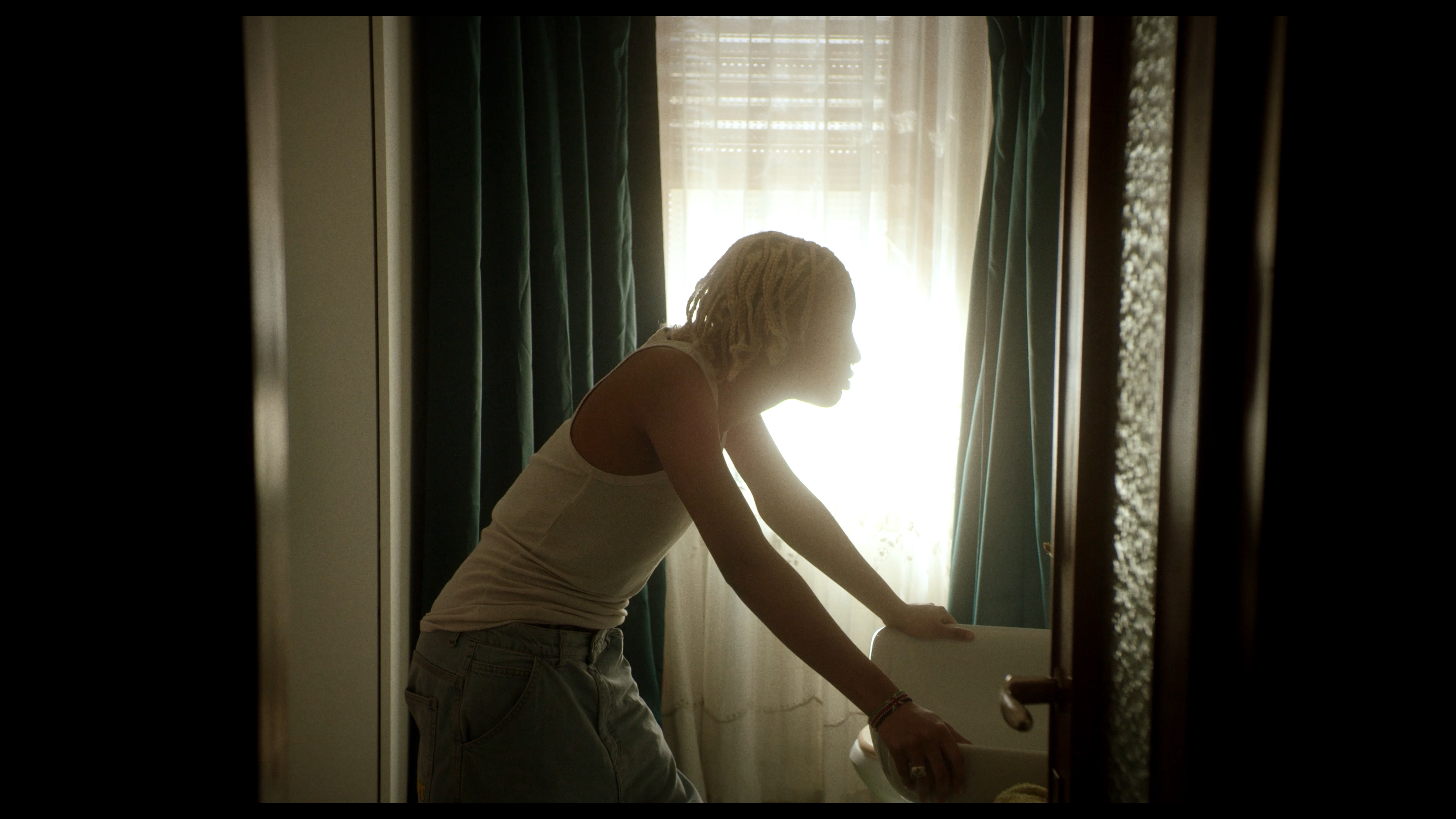 A young man leaning forward beside a sunlit window