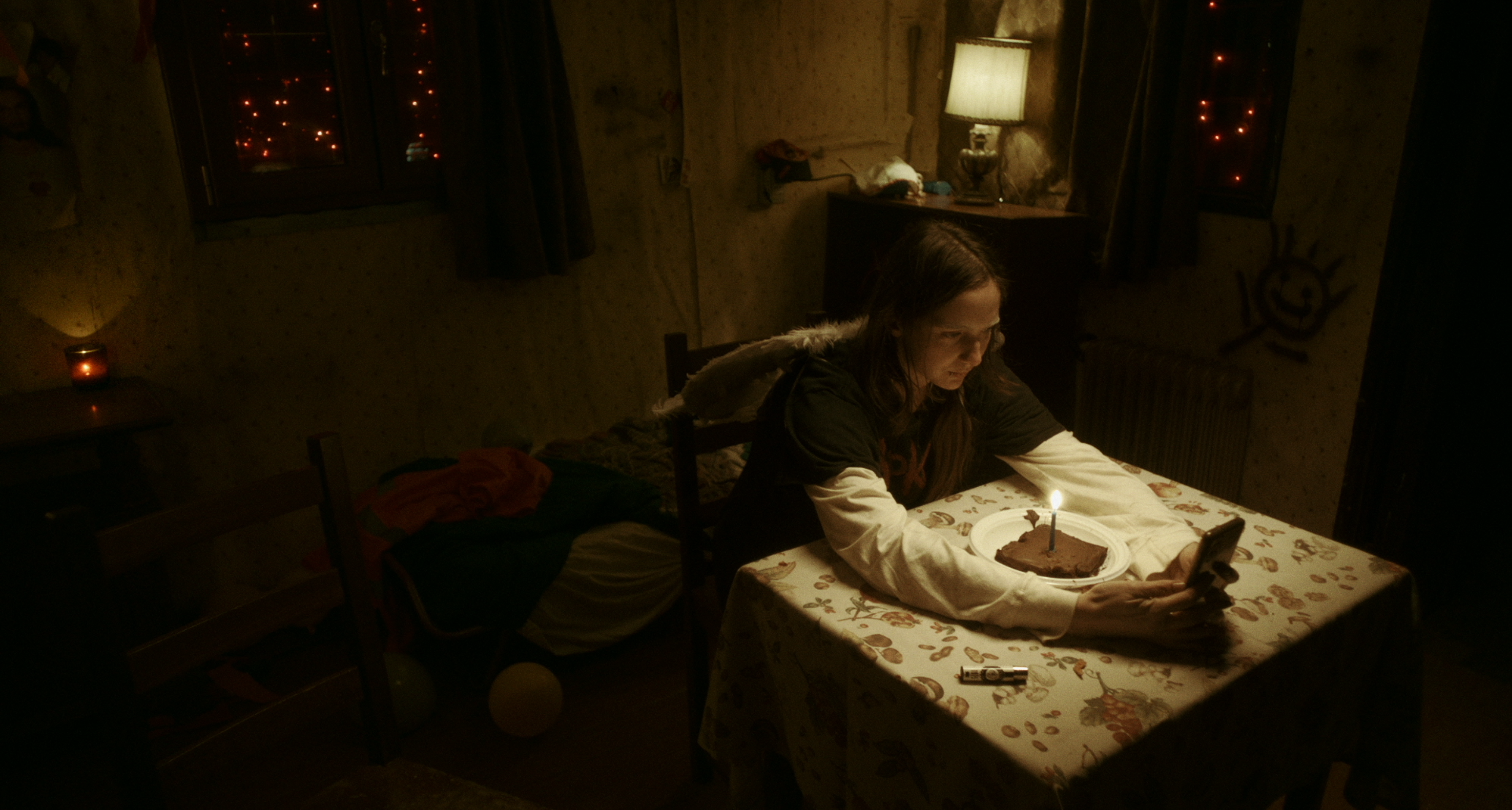 A woman at a table with a birthday candle in a warmly lit room