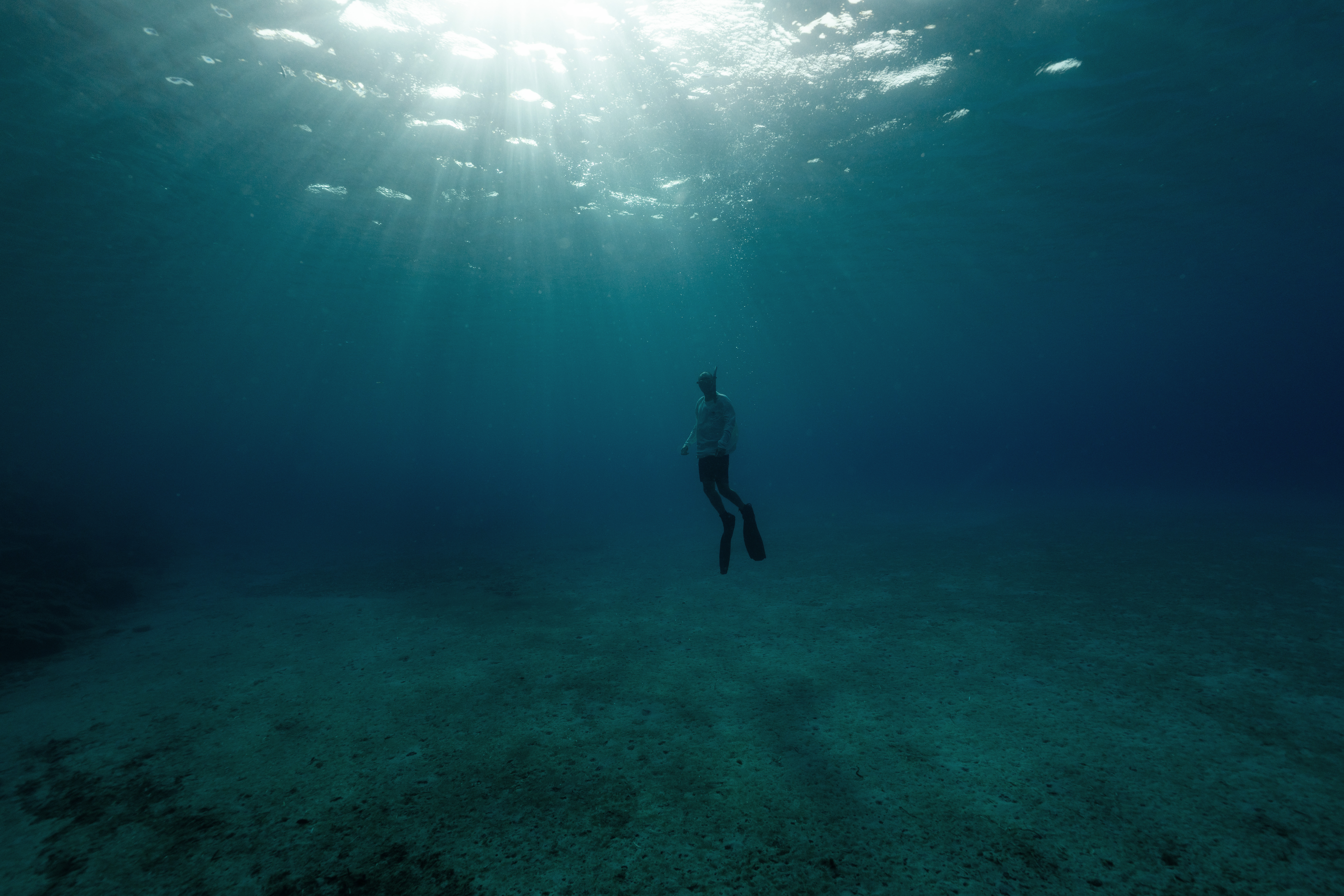 A figure beneath the sunlit surface of the water